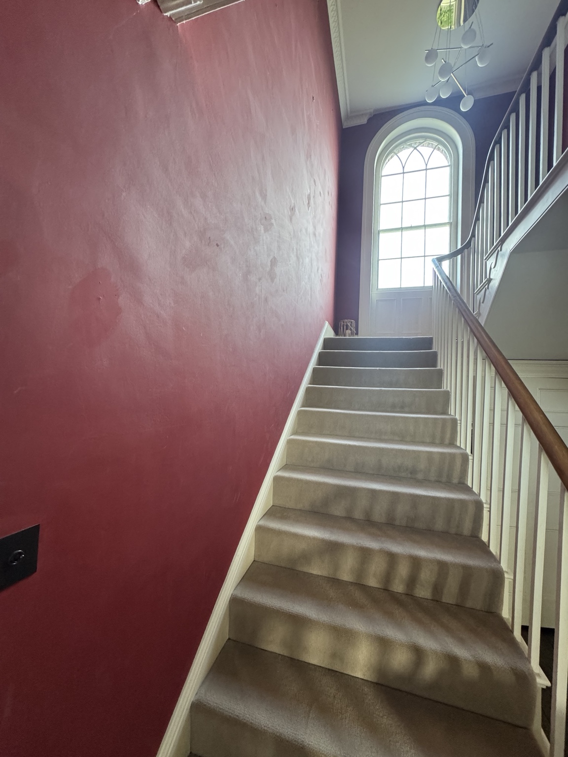 Staircase before, with red walls beside the carpeted steps