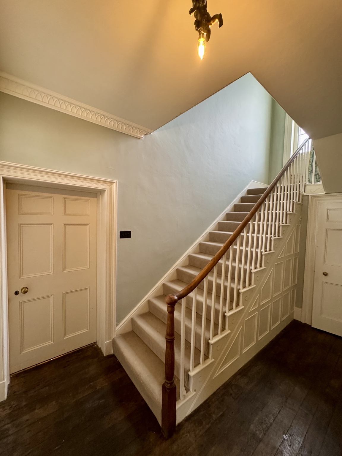 Entrance hall after, with pale walls and white stair joinery